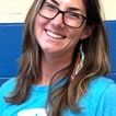 Erin Foss, smiling, in glasses and a light-blue Star Lab T-shirt, against a blue wall.