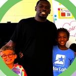 Kareem Robinson, in a black T-shirt, standing with two children in a classroom.