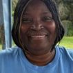 Susan Harvin-Peterson, smiling, in a light-blue T-shirt outdoors.