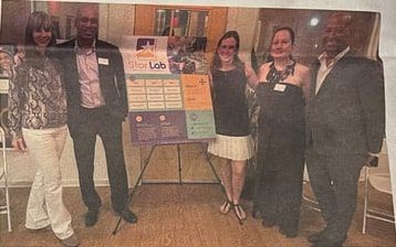 A newspaper photo of five people standing beside a Star Lab poster board at an evening event.