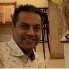 Vivek Gupta, smiling, in a patterned shirt, indoors.
